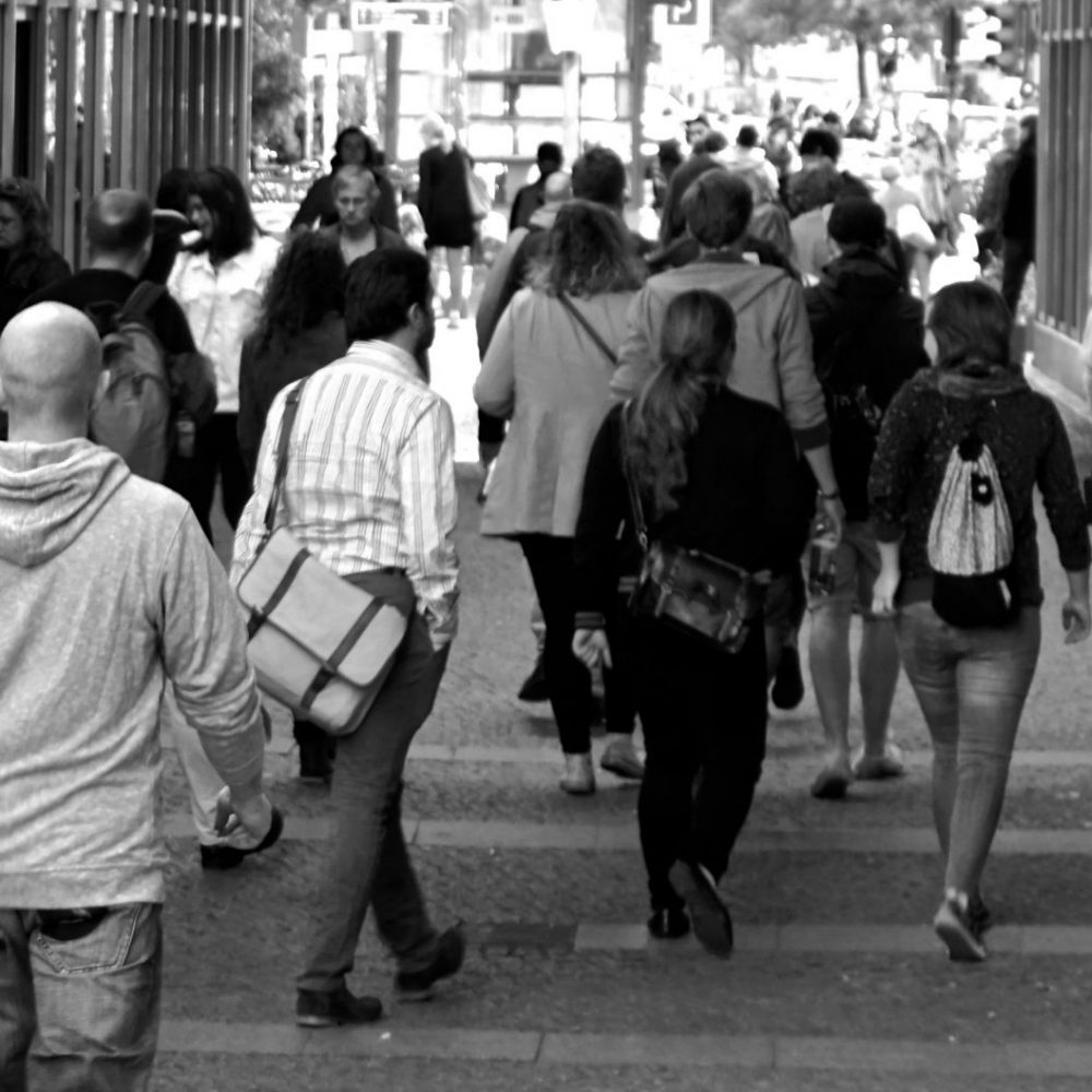 A bustling street scene capturing diverse pedestrians walking outdoors in an urban setting.
